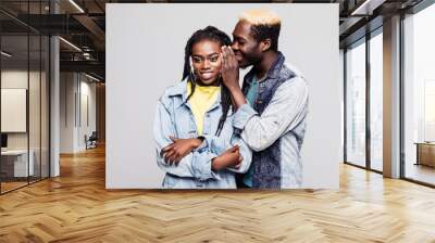 Portrait of a surprised young afro american couple telling secrets isolated over white background Wall mural